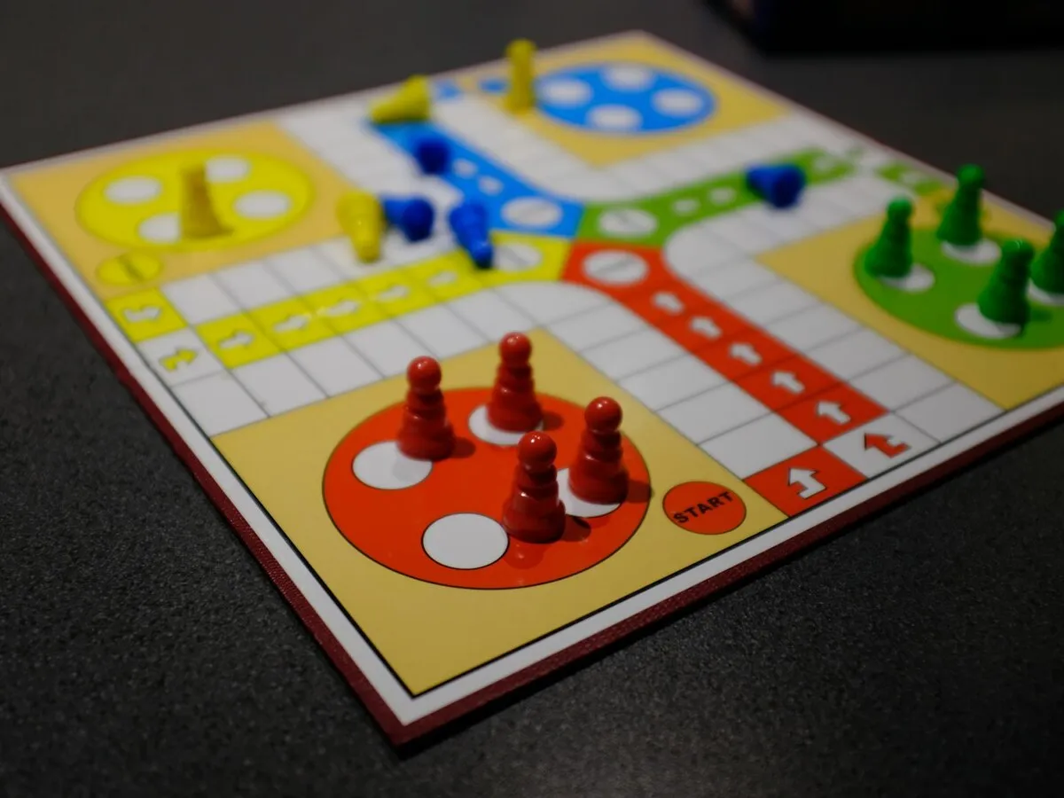A colourful Ludo board with red, green, yellow and blue pawns — a table game, no people